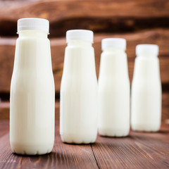 Obraz na płótnie Canvas Bottles with milk, yogurt on a wooden background. Natural dairy products.