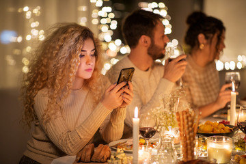 holidays and people concept - woman with smartphone at dinner party with friends at home