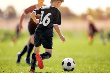 Fototapeta premium Kids in Soccer Club. Sports Summer Training Camp for School Children. Sports Summer Activity for Junior Level Athletes. Boy Running After Ball on Grass