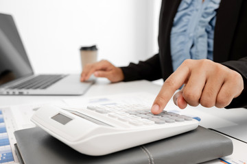 The hands of a male businesswoman use the calculator are analyzing and calculating the annual income and expenses in a financial graph that shows results To summarize balances overall in office