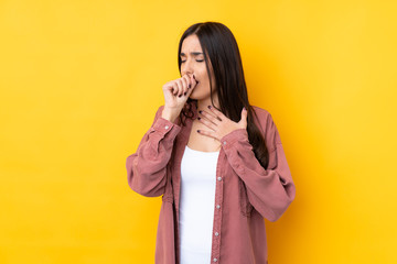 Young brunette woman over isolated yellow background is suffering with cough and feeling bad