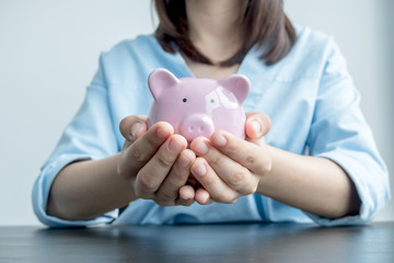 Fototapeta na wymiar A woman's hand holds a piggy bank for saving into a growing business to succeed and save for retirement
