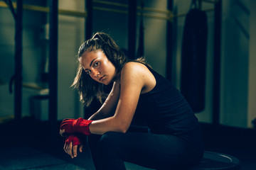 Fototapeta na wymiar woman kickboxing sitting in gym after training