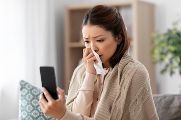 medicine, healthcare and technology concept - sick young asian woman with smartphone having video call or online consultation at home - Powered by Adobe