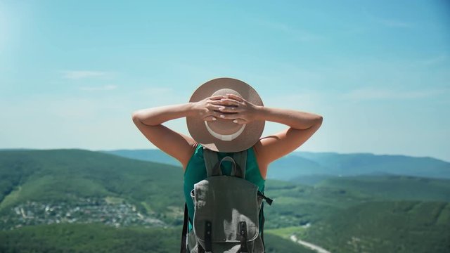 Trendy backpacker woman raising hand admiring nature from mountain. Medium shot on RED camera
