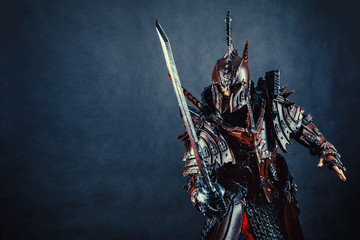 Powerful knight in the armor with the sword. Dark background.