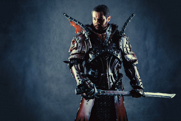 Naklejka premium Powerful knight in the armor with the sword. Dark background.