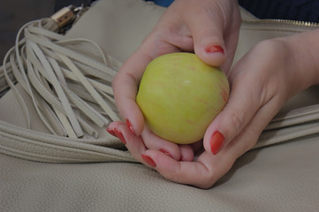 Beauty and fashion. Women's hands with orange nails, holding green apple. Hand care concept. Selective focus.