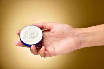 cosmetic cream in hand over yellow background, beauty cream