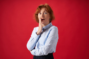 Beautiful redhead woman surprised on red background