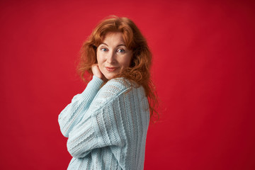 Beautiful smiling redhead woman posing on red background