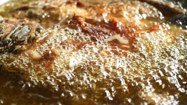 Close up Fried fish in a hot oil pan.

