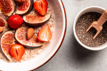 Delicious and healthy oatmeal with figs, strawberries and chia seeds. Healthy breakfast Gluten, lactose free, Fitness food. Long banner format, top view