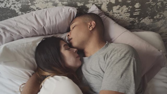 Interracial couple in love sleeping in the bed of his room