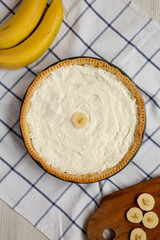 Homemade Tasty Banana Cream Pie on a white wooden table, top view. Flat lay, overhead, from above.