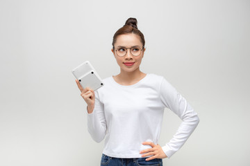 Naklejka premium young woman looking at the camera with a calculator in hand