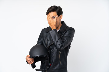 Man holding a motorcycle helmet over isolated white background covering eyes and looking through fingers