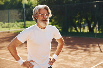 Senior modern stylish man in sunglasses outdoors on the sportive field at daytime