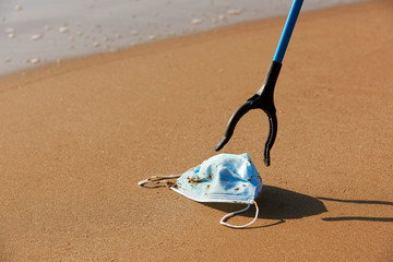 collecting a used surgical mask on the beach