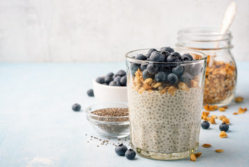 Chia pudding with fresh blueberries and granola in glass on concrete background