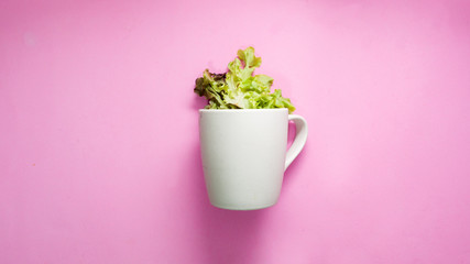 .White coffee cups and green vegetables on pink background