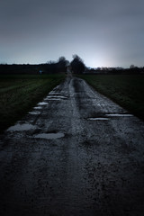 A wet dirt road with potholes at night