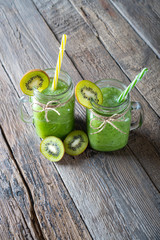 Green smoothie made with fresh fruits and vegetables lying on the wooden background