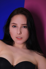 Obraz premium emotional pensive portrait of a pensive brunette girl on a pink-blue background.