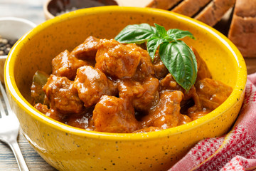 Meat stew in ceramic bowl on rustic wooden background