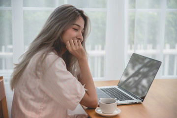 Lazy bored asian woman using laptop in the morning.