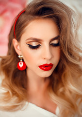 Beauty Portrait of girl with perfect makeup and red jewelry. Beautiful model woman with long curly hairstyle. Eyelashes. Cosmetic eyeshadow. Care and beauty face products.