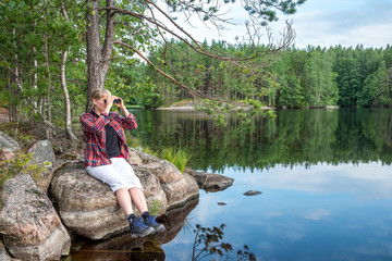 Woman using binoculars while a hiking in the lake