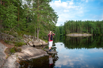 Fototapeta na wymiar Woman using binoculars while a hiking in the lake