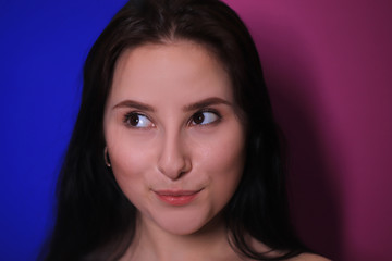Naklejka premium emotional portrait of a brunette girl on a pink-blue background