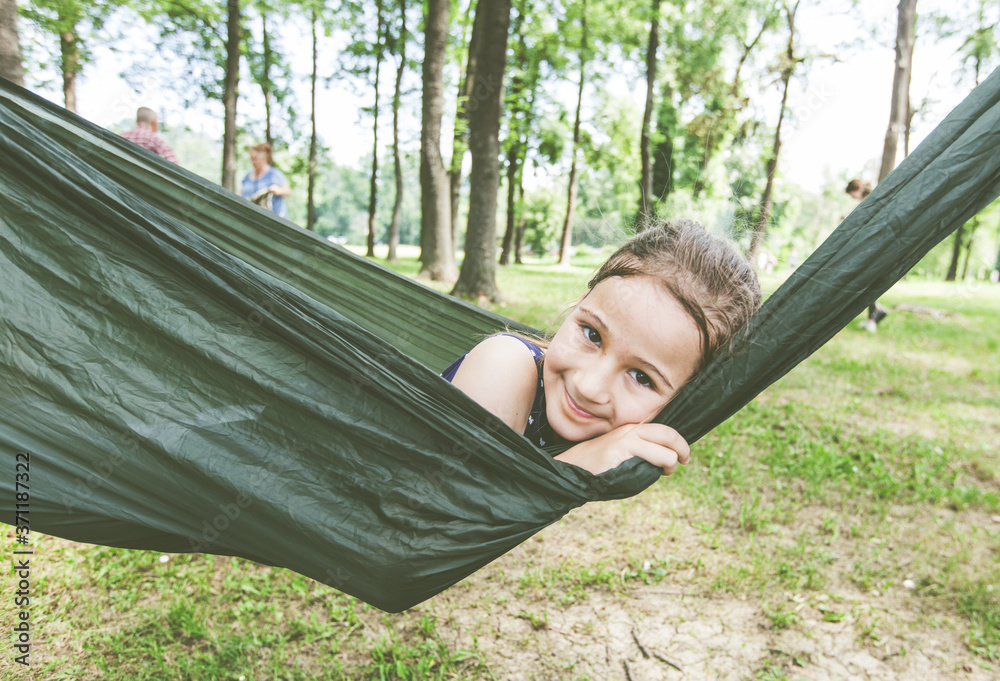 Wall mural Happy portrait of little girl relax on hammock in forest