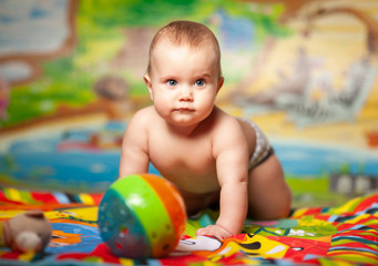 Fototapeta na wymiar Portrait of a cheerful smiling caucasian little six-month-old girl playing in the childrens room with educational toys. Baby products concept