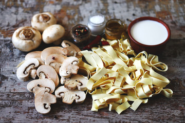 Ingredients for pasta with mushrooms in a creamy sauce. Raw pasta, champignons, cream, spices. Cooking pasta.