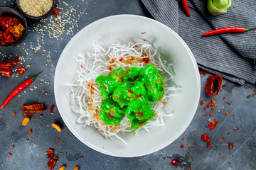 Fried shrimp in wasabi sause with shrimp chips on grey table