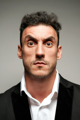 Close up portrait of a man 30-34 years old in a white shirt and a black jacket on a gray background. 