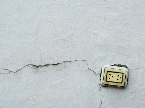 Old Power Socket On White Wall With Crack