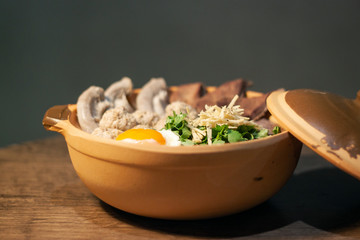Porridge rice or Congee with egg, pork entrails and ginger slide in a clay pot isolated on Dark Slate Gray Concrete Wall background