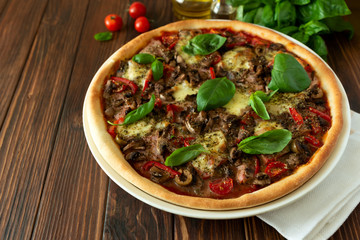 Delicious italian pizza and cherry tomatoes and basil on brown wooden background. Copy space.
