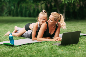 Mother and daughter are engaged in outdoor sports online near their home. The family plays sports together from home. Healthy lifestyle