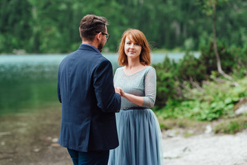 young couple on a walk near the lake surrounded by the mountains