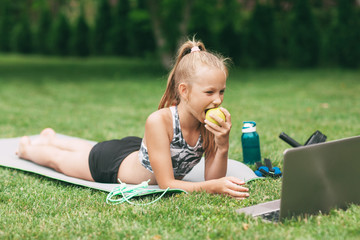 A teenage girl holds an apple and a banana in her hand after undergoing an online outdoor training near her home. Sports. Healthy lifestyle