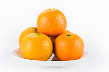 Close-up of several oranges on a white dish.