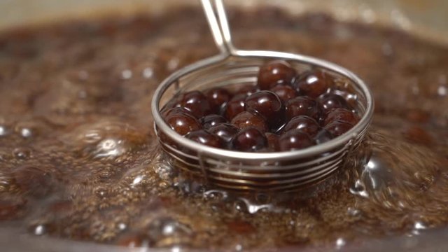 Cooking, boiling brown sugar flavor tapioca pearl balls, ingredient of bubble tea, preparing food and drink, close up, recipe cookbook steps design concept, slow motion.