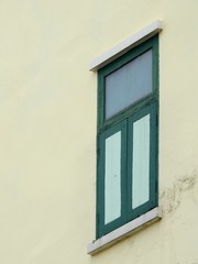 old green window on exterior yellow wall of home