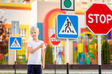 a child stands at a Pedestrian crossing sign and points at it with his finger, traffic rules for...
