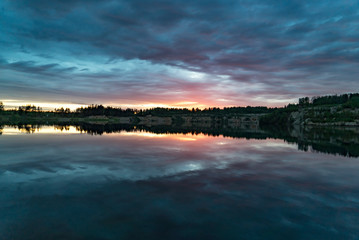 Colorful sunset with a mirror reflection in a forest lake .